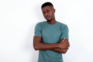 young handsome man wearing green T-shirt over white background frowning his face in displeasure,...