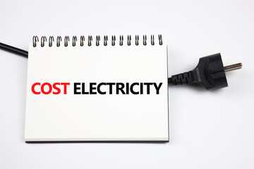 Electricity cost concept. The inscription COST OF ELECTRICITY on a piece of paper and an electric plug.