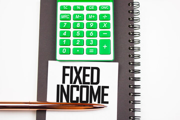FIXED INCOME - concept. The inscription fixed income near the calculator and a notepad with a pen.