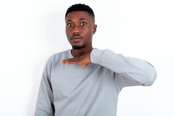 young handsome man wearing grey sweater over white background cutting throat with hand as knife,...