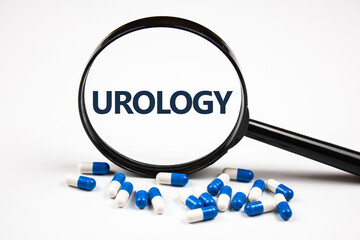 The word UROLOGY through a magnifying glass next to capsules.UROLOGY concept.