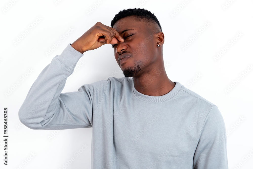 Poster Sad young handsome man wearing grey sweater over white background suffering from headache holding hand on her face