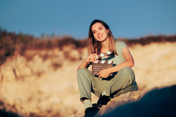 Beautiful Actress Holding a Film Slate in Natural Outdoors Set. Confident actor shooting a scene in nature at golden hour sunlight
