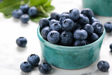 Tasty fresh blueberries on white marble table, closeup