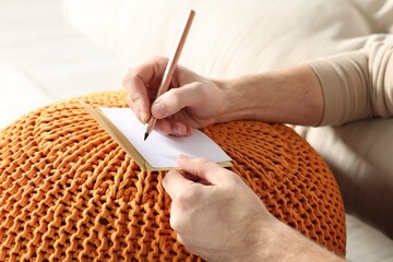 Man writing message in greeting card on orange