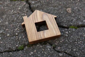 Wooden house model on cracked asphalt. Earthquake disaster