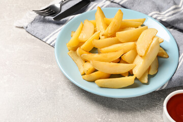 Plate with tasty baked potato wedges and sauce on grey table