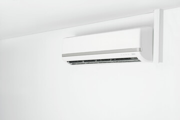 Modern air conditioner on white wall indoors. Space for text