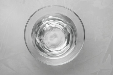 Glass bowl with water on grey table, top view