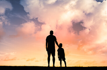 Parent and child young father and son standing together looking at the sunset.. Parenting, and family relationship concept.  - obrazy, fototapety, plakaty