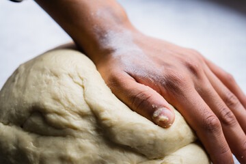 Hand of an unrecognizable person on dough to prepare bread.