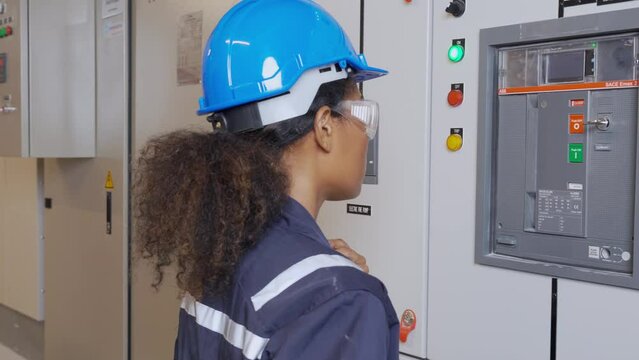 Electrical young asian woman engineer examining maintenance cabinet system electric and using tablet in control room at industrial factory, technician or electrician inspection power distribution.
