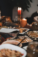 Halloween dishes on a table full of candlesticks and candles and other decorations, muffins, salads, cookies, pies and other dishes, close-up shot, dark blurry background