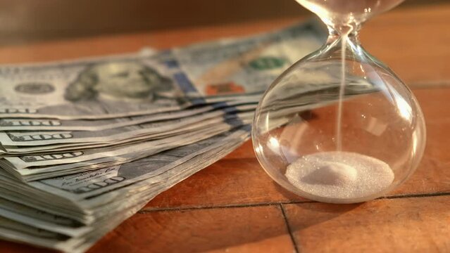 Close up timeglass and banknote on wooden table. Saving money concept.
