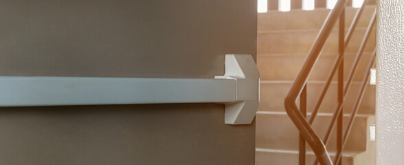 Emergency fire exit door. Closed up latch and rusty door handle of emergency exit. Push bar and rail for panic exit. Open one way door. steel of handle for the white door fire exit	