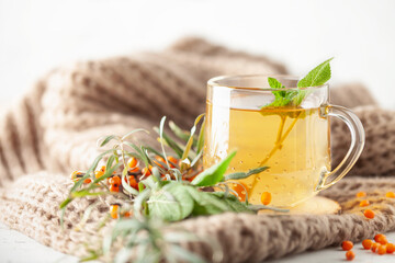 Sage, mint, sea buckthorn, herbal tea in a glass cup with fresh  leaves on wooden background....
