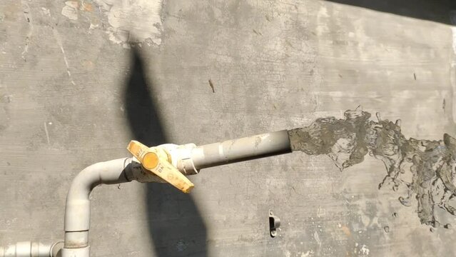 Plastic pipe pumping, gushing or discharge small manufacturing industry polluted, contaminated and dirty brown waste water chemical effluent out after industrial use. Pollution and irrigation concept.