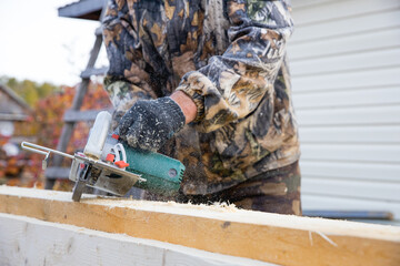Hands of carpenter work with grinder saw on wooden boards