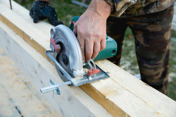 Hands of carpenter work with grinder saw on wooden boards