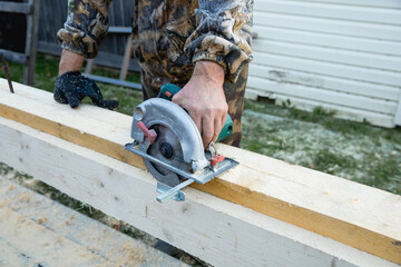 Hands of carpenter work with grinder saw on wooden boards