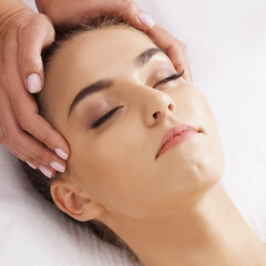 Naklejka premium Beautiful, young and healthy woman having face massage in spa salon. Hands of professinal masseur. Spa, health and healing concept.