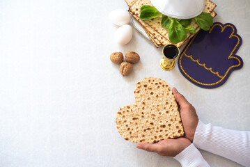 Woman's hands holds Matzah shape of heart. Traditional of Jewish Holiday on Passover. Home symbol of lovely family. top view, layout. love and care. Gift for lovers. Feeling in love and blissful life
