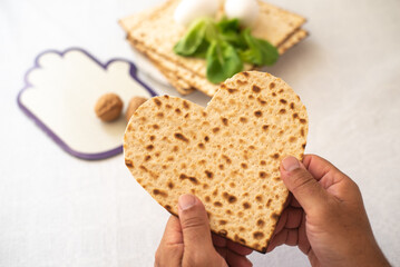 Man's hands holds Matzah shape of heart. Traditional of Jewish Holiday on Passover. Home symbol of lovely family. top view, layout. love and care. Gift for lovers. Feeling in love and blissful life