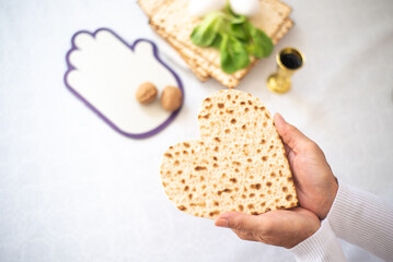 Woman's hands holds Matzah shape of heart. Traditional of Jewish Holiday on Passover. Home symbol of lovely family. top view, layout. love and care. Gift for lovers. Feeling in love and blissful life