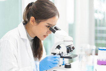 Medical development research laboratory, science young woman scientist in glasses, glove looking under microscope for test analysis samples in lab. Microbiology, analysing biochemicals for medicine