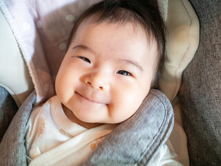 Smiling Asian baby in a stroller