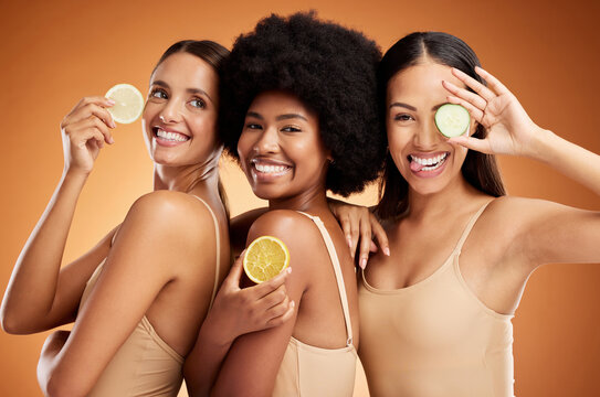 Diversity, Beauty And Friends, Women And Lemon For Skincare, Wellness And Health On Orange Studio Background. Smile, Models And Fruit, Lemons Or Lime Citrus For Vitamin C, Nutrition And Healthy Skin.