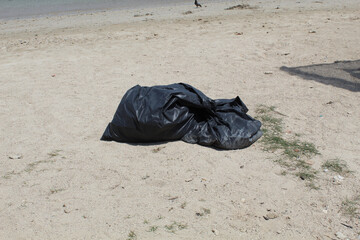 A black big trash bag on the beach