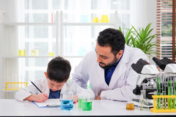 Lovely Asian young boy in lab coat enjoy doing an experiment and studying a science. 