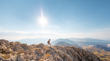 the girl is walking along the ridge of the mountain.