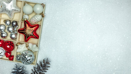 christmas stars and glass balls in wooden box with pine cones on silver background