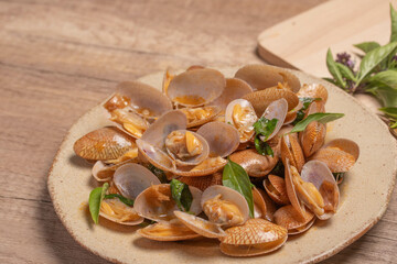 Stir fried clams with basil leaves in a white bowl