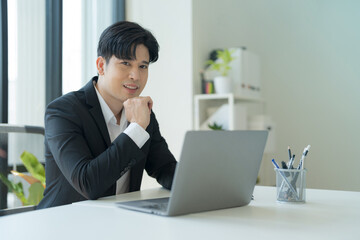 Attractive businessman working on laptop in workstation office.
