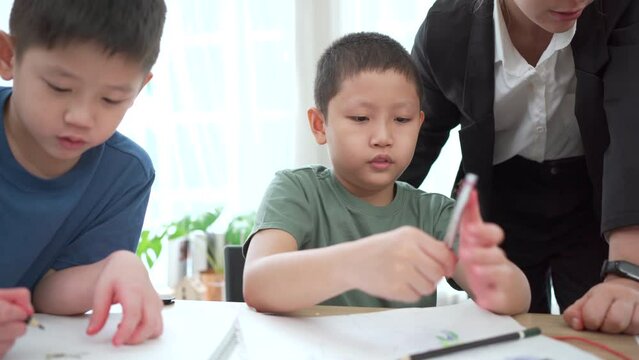 Asian lovely little boy enjoy drawing a picture and painting on the paper in art classroom. 