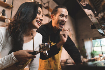 happiness two waiter teaching woman with apron to use a coffee machine for make a coffee. the happiness men and woman in bakery small business on waiter and waitress uniform.