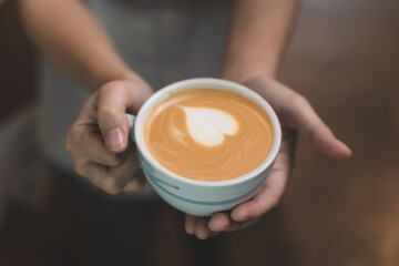 waitress handing and sip a coffee and present coffee with smiling. the happiness woman in coffee shop on waitress uniform and service customer.