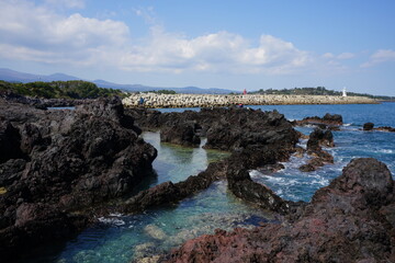 Obraz premium clear rock coast and distant lighthouse