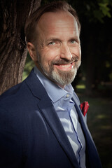 Detail of man in blue suit with shirt and tie posing in summer park