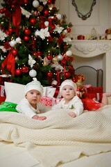 Two babies are lying in a festive outfit on the background of New Year and Christmas decorations. The concept of holidays