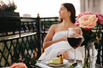 A glass of wine and a piece of cheesecake on the background of a woman's silhouette.