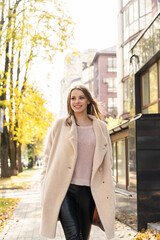 Fototapeta premium Happy Woman wearing coat walking in the sunny city