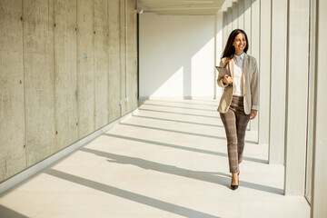 Young businesswoman walking on modern office hallway - Powered by Adobe