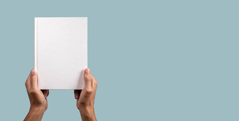 Paper business book mock up in male hand on blue banner with copy space. Hard cover mockup, blank template