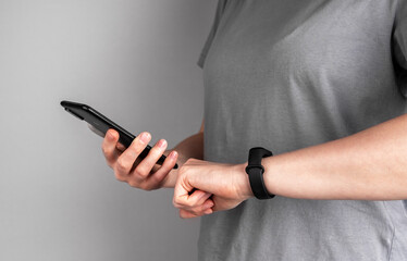 Female athlete hands with mobile phone and fitness bracelet