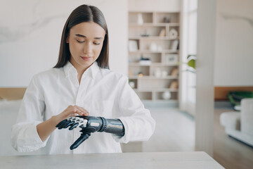 Girl adjust settings of bionic prosthetic arm, touch sensory panel on upper side of artificial hand
