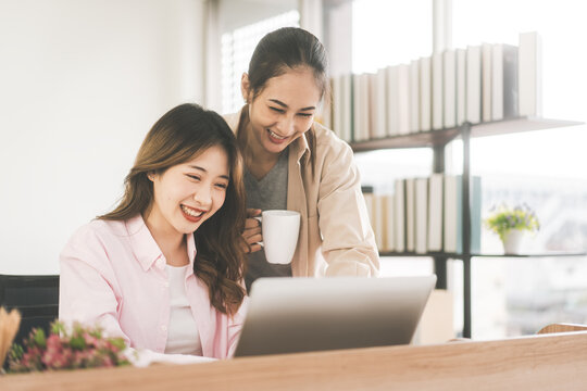 Two Young Adult Asian Woman Couple At Home Using Laptop For Shopping Online And Work